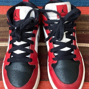May include: A pair of red and black sneakers with white accents. The sneakers have black laces and a white midsole.