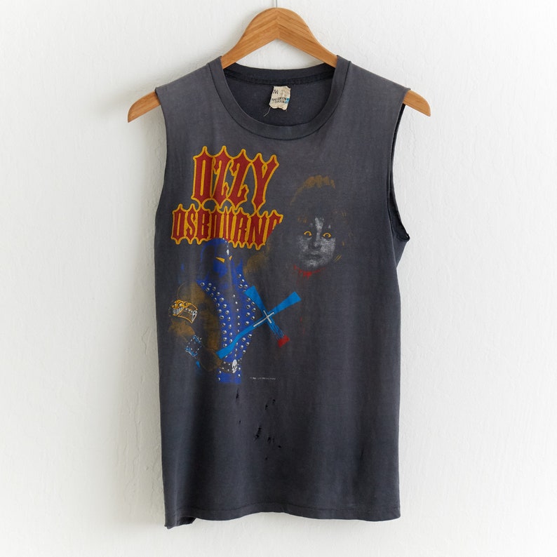 Puede incluir: Camiseta gris sin mangas con una imagen en blanco y negro de Ozzy Osbourne y un gato negro. El texto "OZZY OSBOURNE" est&aacute; impreso en rojo y amarillo.