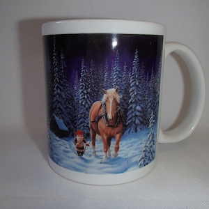 May include: White ceramic mug featuring a winter scene with a brown horse, a small figure, and snow-covered pine trees under a dark purple sky. The mug has a curved handle and a glossy finish, suitable for hot beverages.