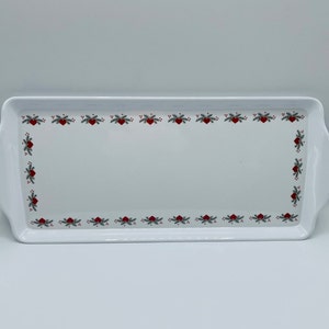 May include: A rectangular white serving tray with rounded handles. The tray is decorated with a border of red hearts, green sprigs, and red berries. The tray is suitable for serving food.