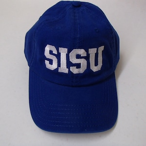 May include: A royal blue baseball cap with the word "SISU" embroidered in white block letters across the front. The cap has a curved brim and a fabric strap closure on the back.