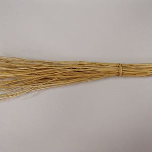 May include: A handmade broom made of natural straw. The straw is a light tan color and is bundled together with twine. The broom is designed for sweeping and cleaning.