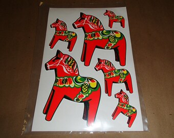 May include: Sheet of stickers featuring six red Dala horses with intricate floral and decorative patterns in green, yellow, and white. The horses are in various sizes, with a traditional folk art style.
