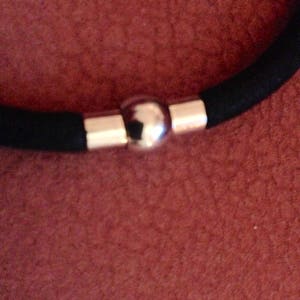 May include: A black elastic bracelet with a silver ball clasp.