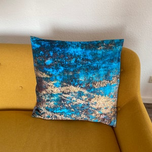 May include: A blue and gold patterned cushion on a yellow sofa.