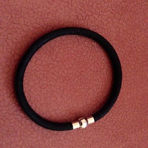 May include: A black elastic bracelet with a silver magnetic clasp.
