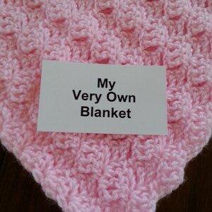 May include: A pink crocheted blanket with the text "My Very Own Blanket" on a white card.