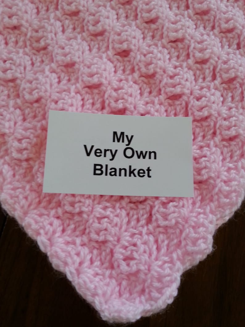May include: A pink crocheted blanket with the text "My Very Own Blanket" on a white card.