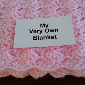 May include: A pink crocheted blanket with a white card that says "My Very Own Blanket".