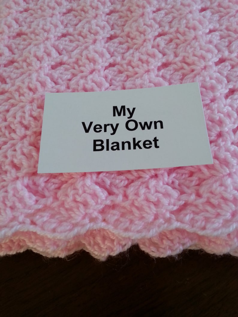 May include: A pink crocheted blanket with a white card that says "My Very Own Blanket".
