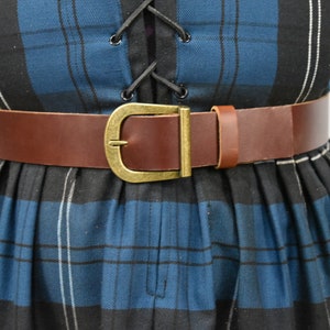 May include: A brown leather belt with a brass buckle. The belt is worn over a blue and black plaid dress.