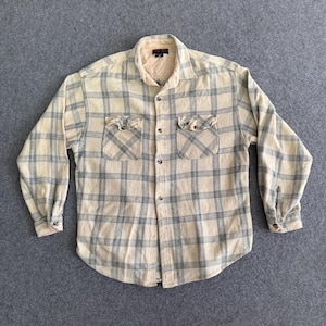 May include: Cream-colored, long-sleeved flannel shirt with a blue plaid pattern. Features two chest pockets and a button-down front. The collar and cuffs are a lighter cream color.