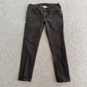 Pu&ograve; includere: Un paio di jeans neri. I jeans hanno un classico design a cinque tasche, una chiusura con bottone e cerniera e sono realizzati in denim scuro. Le cuciture sono di un colore a contrasto e i jeans sembrano essere in buone condizioni.