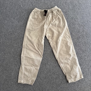 K&ouml;nnte beinhalten: Beigefarbene Baumwollhose mit elastischem Bund und einem schwarzen Innenetikett. Die Hose hat eine lockere Passform mit sichtbaren vertikalen Nahtdetails an der Vorderseite jedes Beins und eine leicht zulaufende Silhouette an den Kn&ouml;cheln.