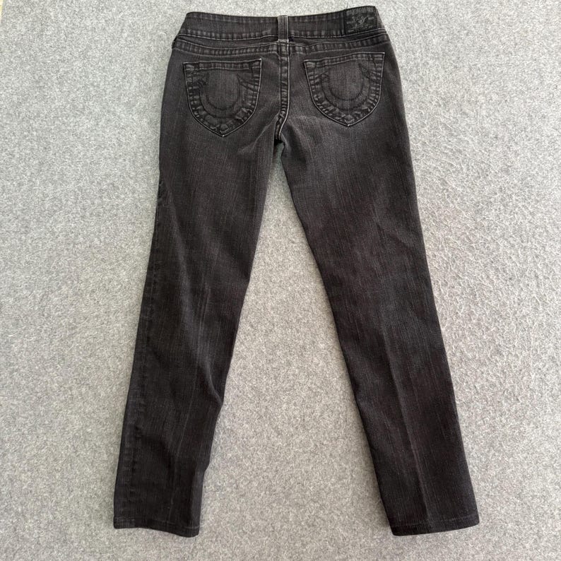 Pu&ograve; includere: Jeans in denim grigio scuro con un classico design a cinque tasche. I jeans presentano cuciture decorative sulle tasche posteriori e una piccola toppa con logo in vita. I jeans sono a gamba dritta.