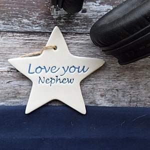 May include: White ceramic star ornament with blue lettering that reads "Love you Nephew".