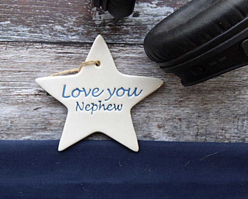 May include: White ceramic star ornament with blue lettering that reads "Love you Nephew".
