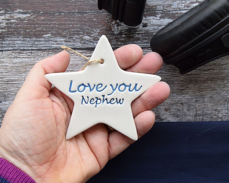 May include: White ceramic star ornament with blue lettering that reads "Love you Nephew".