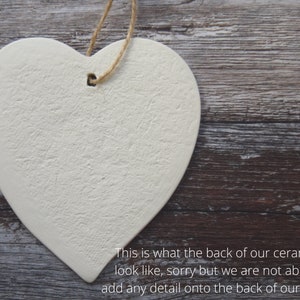 May include: A heart-shaped ceramic ornament with a textured surface and a hole for hanging. The ornament is off-white and has a natural twine string. The text on the image says, "This is what the back of our ceramics look like, sorry but we are not able to add any detail onto the back of our items."