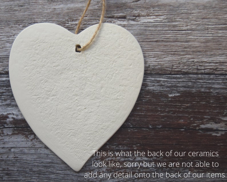 May include: A heart-shaped ceramic ornament with a textured surface and a hole for hanging. The ornament is off-white and has a natural twine string. The text on the image says, "This is what the back of our ceramics look like, sorry but we are not able to add any detail onto the back of our items."