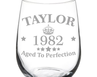 May include: A clear glass wine glass with the text "TAYLOR 1982 Aged To Perfection" and a crown design etched on the front.
