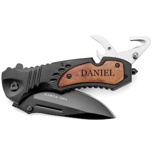 May include: A black folding pocket knife with a wood handle. The handle has the name "DANIEL" engraved on it. The knife has a bottle opener, a seatbelt cutter, and a glass breaker.