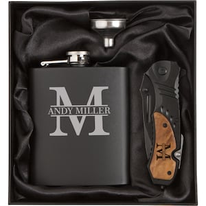 May include: A black gift box with a black flask engraved with the letter "M" and the text "ANDY MILLER". The box also contains a black pocket knife with a wood handle engraved with the letter "M" and the text "EVERYTHING".