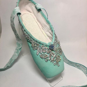 May include: Mint green ballet slipper with a white lace ribbon and silver and crystal embellishments.