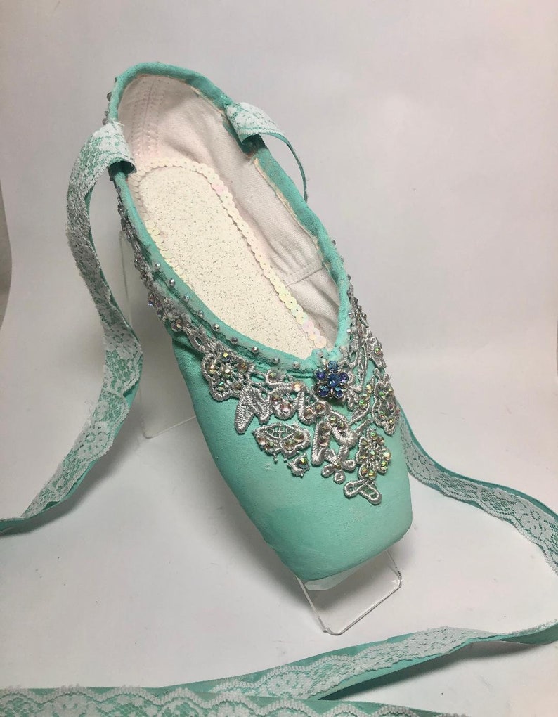 May include: Mint green ballet slipper with a white lace ribbon and silver and crystal embellishments.