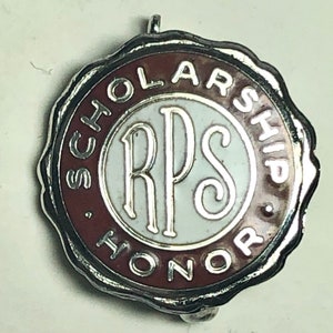 May include: A silver and maroon colored pin with the text "SCHOLARSHIP HONOR" surrounding a white circle with the text "RPS" in silver.