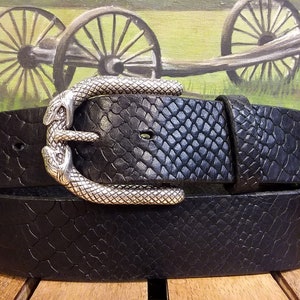 Könnte beinhalten: Ein schwarzer Ledergürtel mit einer schlangenförmigen Schnalle. Der Gürtel hat ein strukturiertes Schlangenhautmuster.