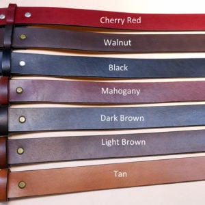 May include: Seven leather belts in various colors, including tan, light brown, dark brown, mahogany, black, walnut, and cherry red.