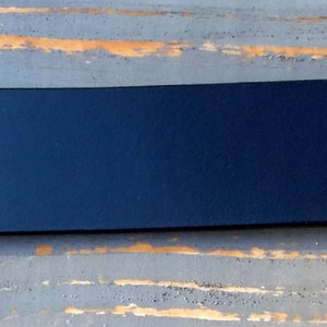 May include: A dark blue, rectangular, flat, smooth, and solid piece of material.