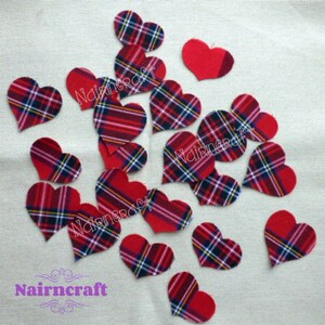 May include: A collection of heart-shaped fabric cutouts featuring a red, black, white, and yellow plaid pattern, alongside a few solid red heart-shaped fabric cutouts. The word Nairncraft is printed in purple text at the bottom left corner.
