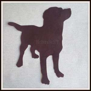 Peut inclure: Une découpe en feutrine marron foncé représentant la silhouette d'un chien debout avec la queue pointée vers le haut. La forme présente une surface unie et lisse, avec le texte Nairncraft imprimé en lettres fines et claires au centre.