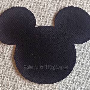 May include: A black fabric patch shaped like a mouse head silhouette with two large circular ears. The text Nalen's knitting World is embroidered in a thin, light-colored thread across the lower center of the black fabric surface.