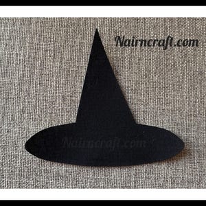 May include: A flat, black, witch hat silhouette cutout featuring a pointed crown and a wide, oval brim. The text 'Nairncraft.com' is printed in a dark, stylized font across the upper right section of the black witch hat shape.