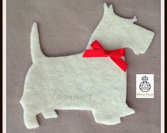 May include: A cream-colored felt cutout in the shape of a Scottish Terrier dog, featuring a bright red satin ribbon bow tied around its neck. The word Nairncraft is embossed on the body, and a Harris Tweed logo is visible in the corner.