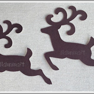 May include: Two dark brown, flat, die-cut reindeer silhouettes in a leaping pose with ornate, curled antlers. Each reindeer figure features the word Nairncraft embossed in a light, subtle font across the centre of the body shape.