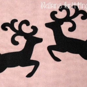May include: Two black reindeer silhouettes embroidered on a light pink fabric background. The reindeer are depicted in a leaping pose with large, curved antlers. The text "Nairns knitting World" is visible in the upper right corner.