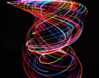 May include: Abstract image of colorful light trails in a swirling pattern against a black background. The light trails are red, blue, green, yellow, and pink.