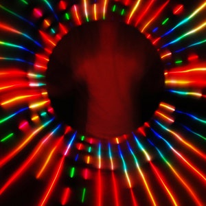 May include: Abstract image of a colorful light show with red, orange, yellow, green, blue, and purple lights radiating outward from a central point.
