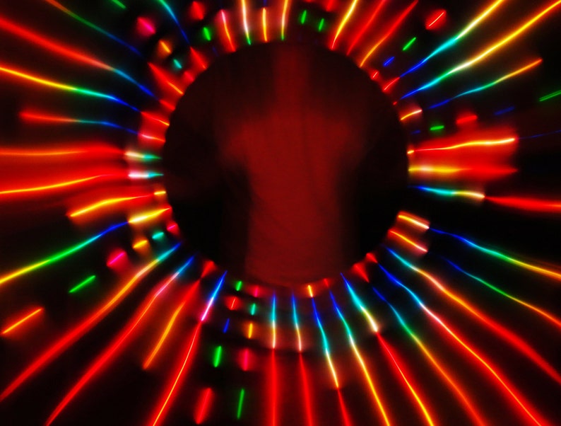 May include: Abstract image of a colorful light show with red, orange, yellow, green, blue, and purple lights radiating outward from a central point.