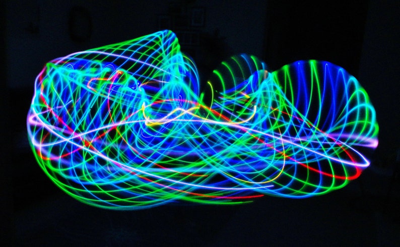 May include: Abstract light painting with swirling lines of blue, green, red, and white light on a black background.