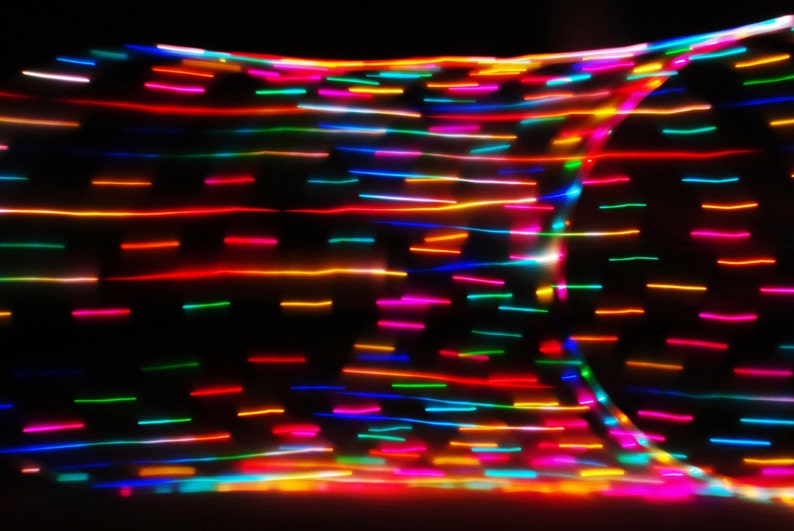 May include: Abstract image of colorful, blurred lines of light against a black background. The lines are arranged in a grid pattern, creating a dynamic and energetic visual.