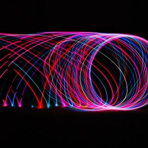 May include: Abstract image of colorful light trails in pink, blue, and red, creating a swirling, circular pattern against a black background.