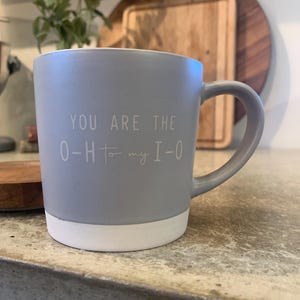May include: A gray ceramic mug with a white rim. The mug has the text "You are the O-H to my I-O" printed on it.