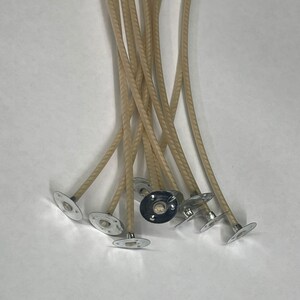 Puede incluir: Un paquete de diez mechas de vela beige con bases metálicas. Las mechas son trenzadas y tienen una superficie texturizada.