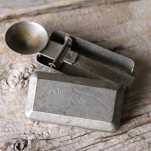 May include: A vintage metal prescription scale with a rectangular base and a circular weighing pan. The top of the base is engraved with the text Dr. C.H. Fitch's Prescription Scale, featuring decorative scrollwork and a patent date visible below.