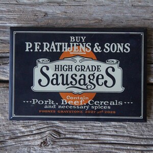 P. F. Rathjens & Sons High Grade Sausages Pressed Tin Advertising Sign from American Art Works in Coshocton Ohio
